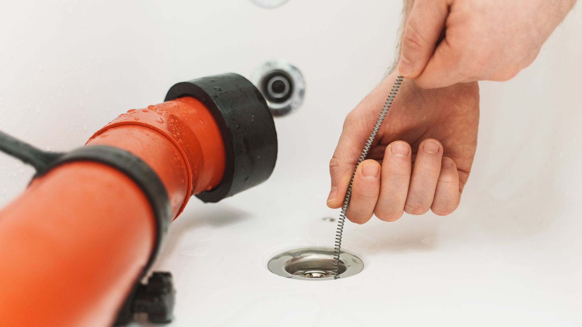 A person fixing a drain in a bathroom